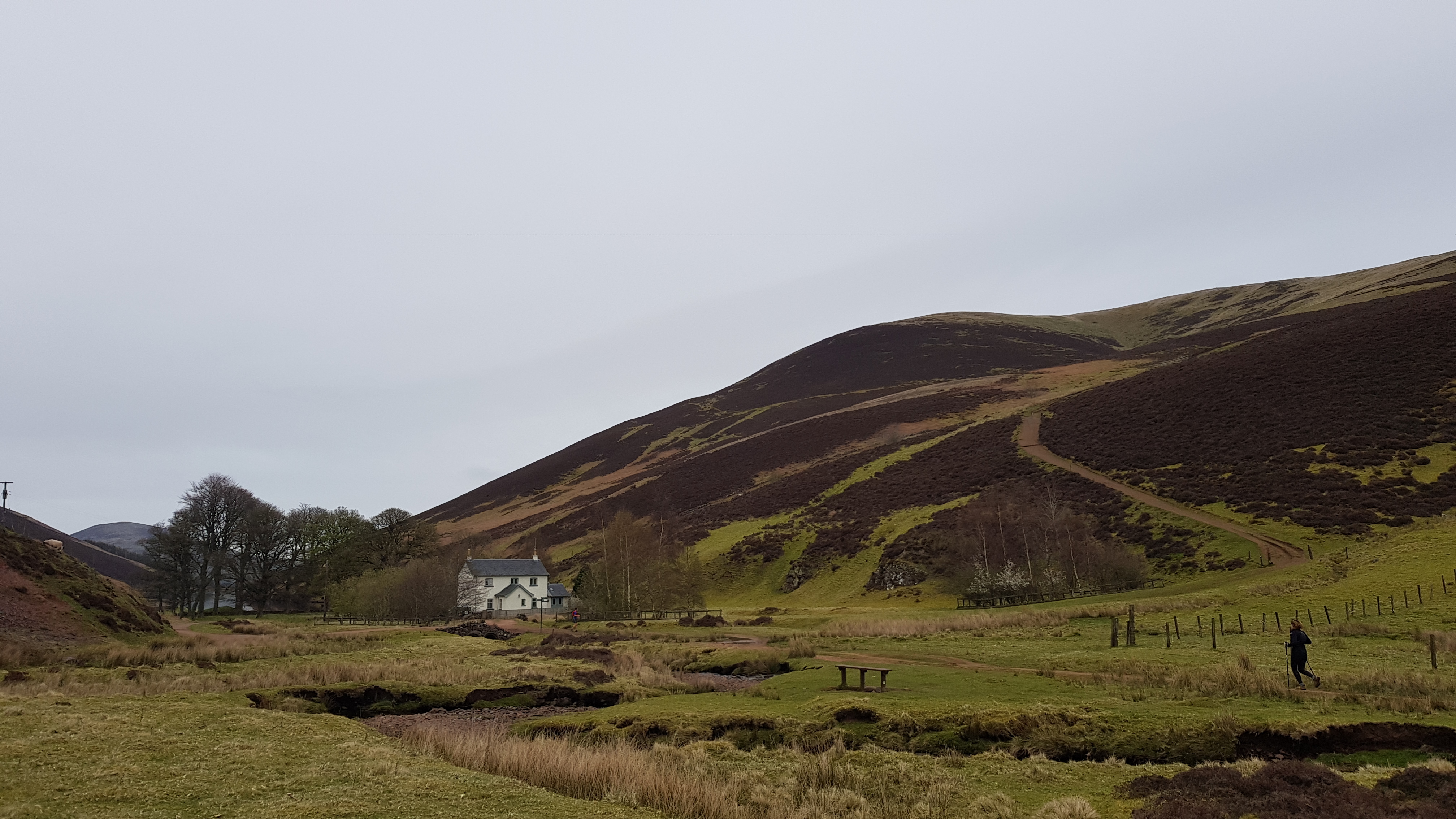 An early-spring photo of a farmhouse in a narrow glen.